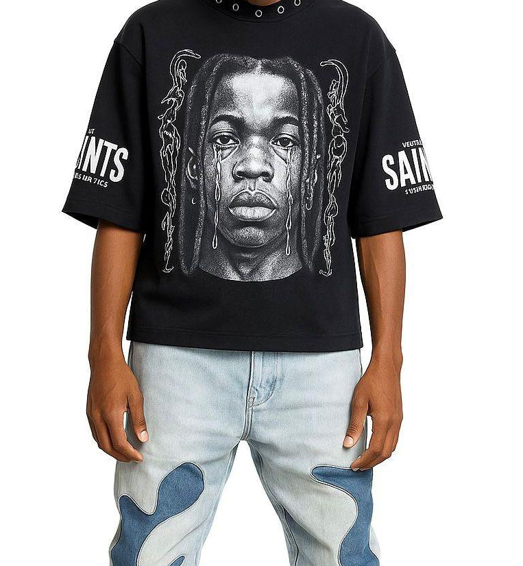 Person wearing a black t-shirt with a graphic design and light blue jeans on a white background